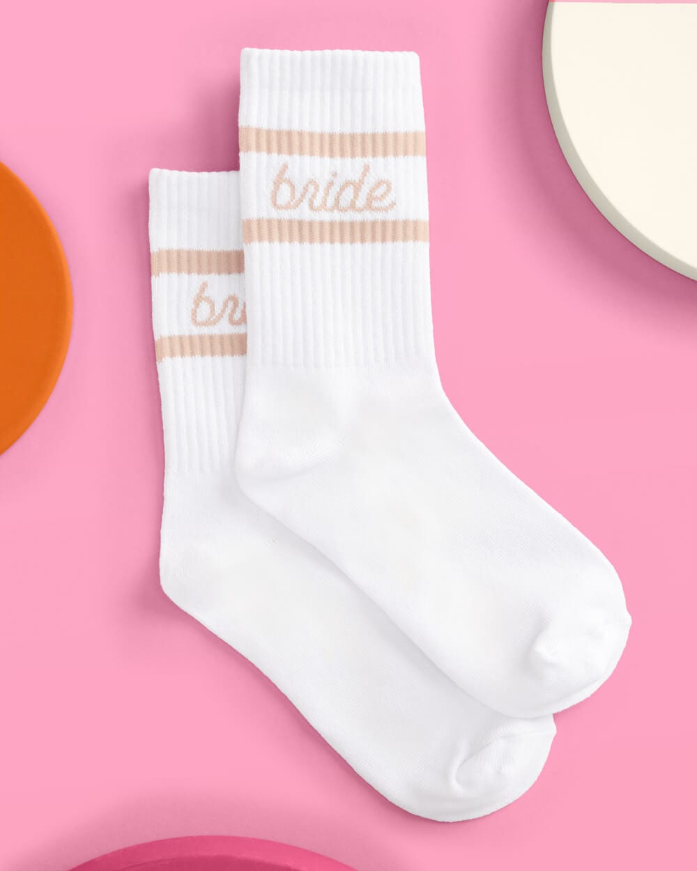 White crew socks with beige stripe detail and "bride" text on pink background