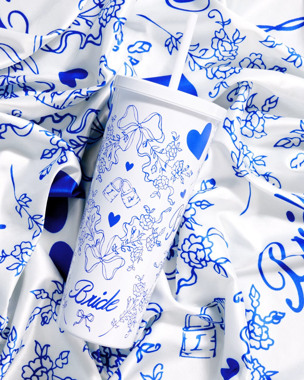 White 24 oz tumbler with blue floral line drawings, hearts, and "Bride" script text design.