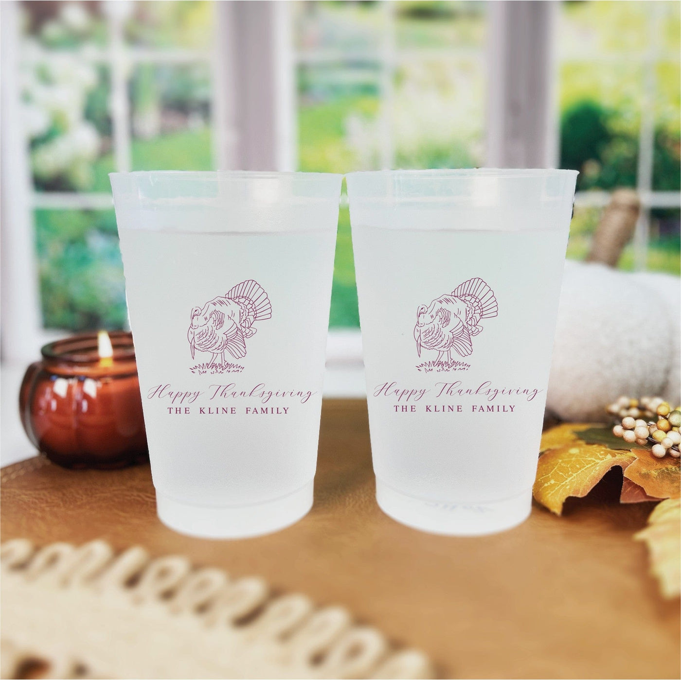Two frosted translucent plastic cups are personalized with a reddish-brown turkey graphic, designed for use as drinkware at a Thanksgiving or fall celebration.
