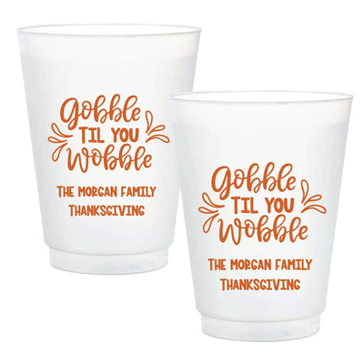 Two translucent white plastic party cups for a Thanksgiving gathering, featuring an autumnal orange design.