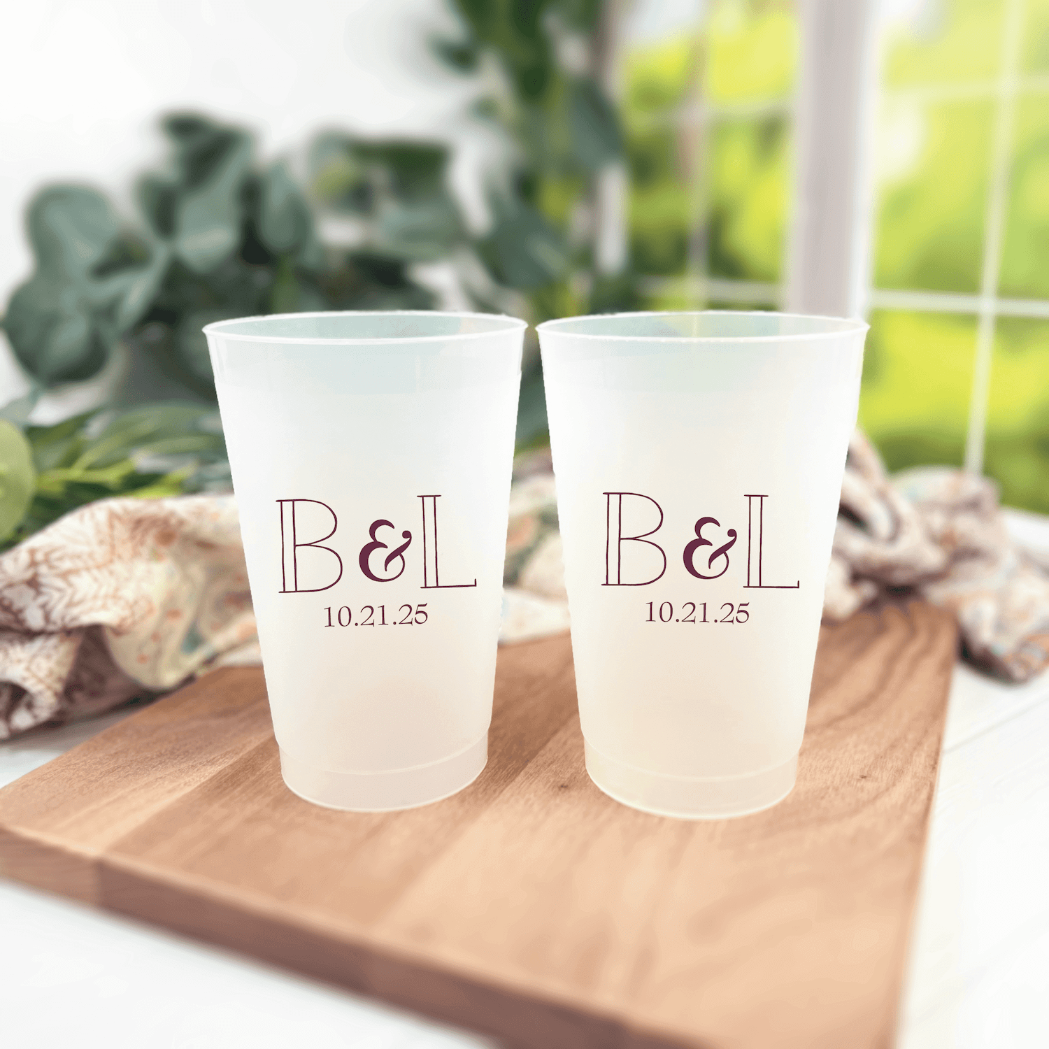 Two frosted cups with "B&L" monogram and wedding date "10.21.25" printed in elegant lines on wooden serving board