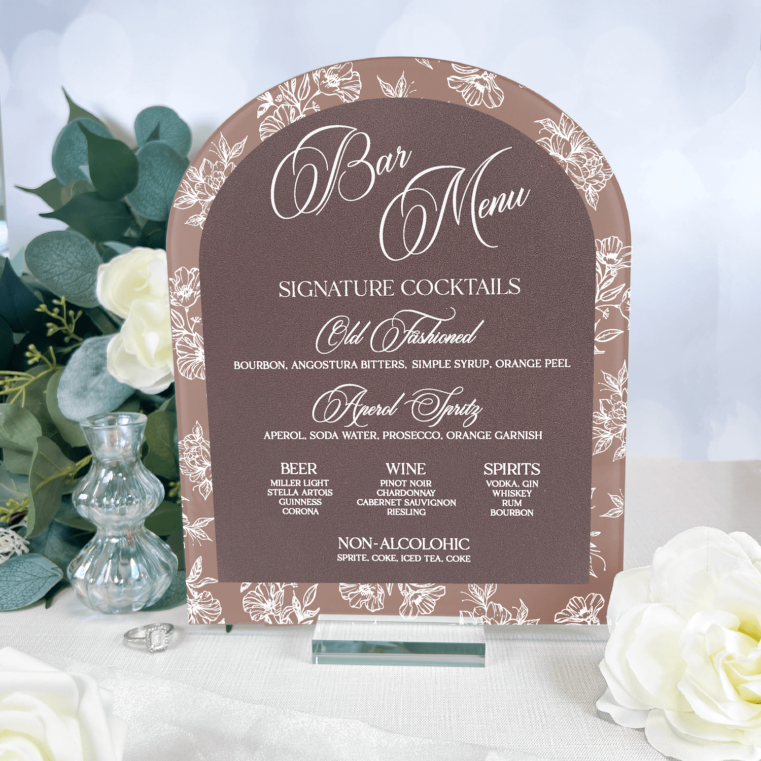 Arched acrylic bar menu sign with toile floral design, listing signature cocktails and drink options for a wedding celebration