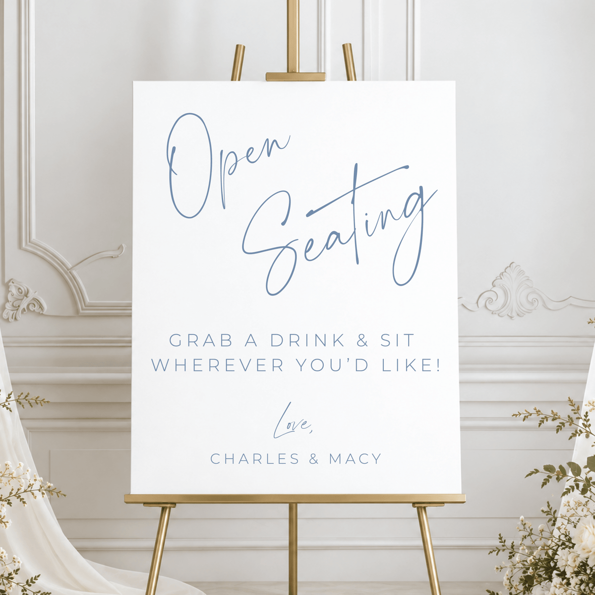 Personalized open seating wedding sign with dusty blue lettering, displayed on a gold easel with elegant white wedding decor.