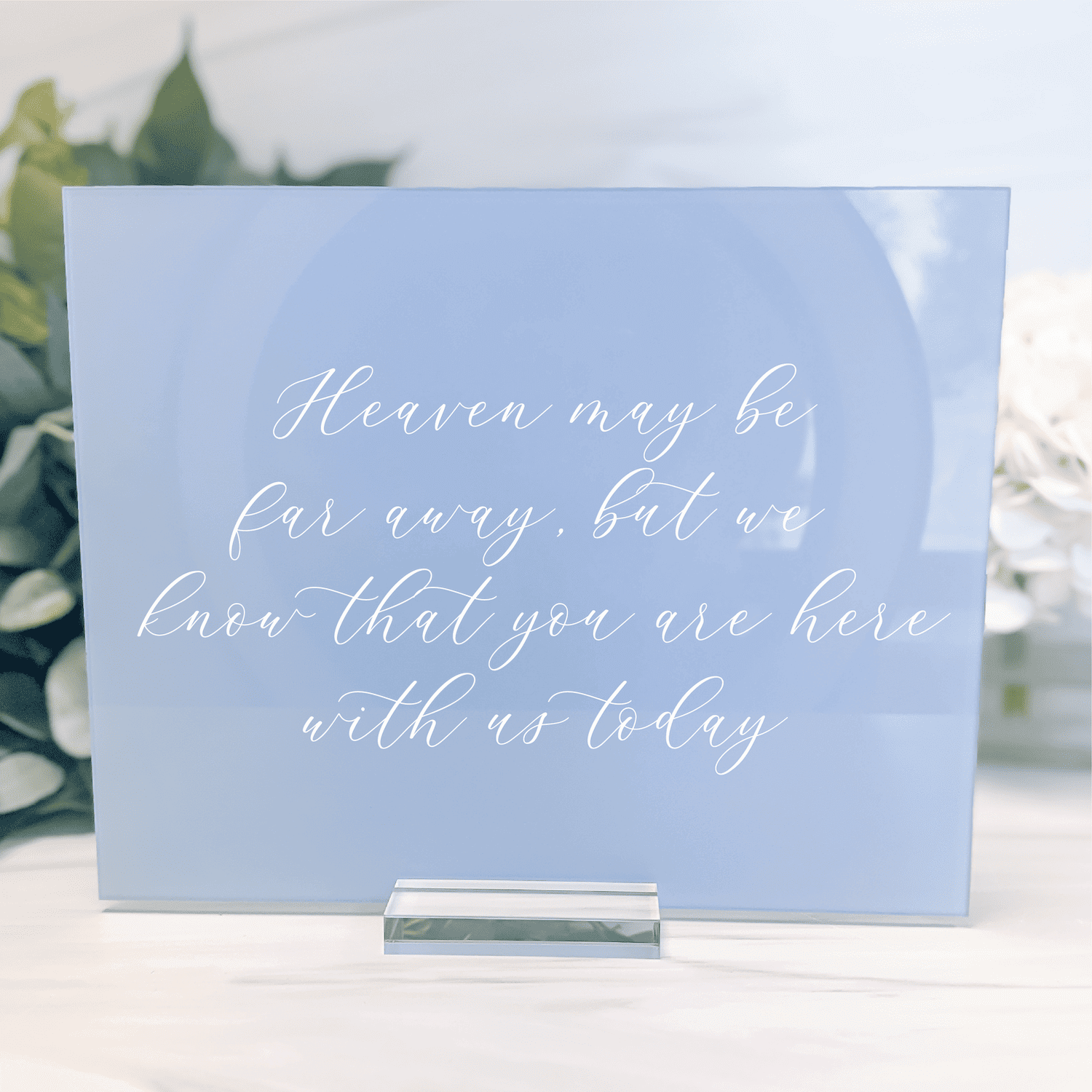 Light blue frosted acrylic sign with white script text reading "Heaven may be far away, but we know that you are here with us today"