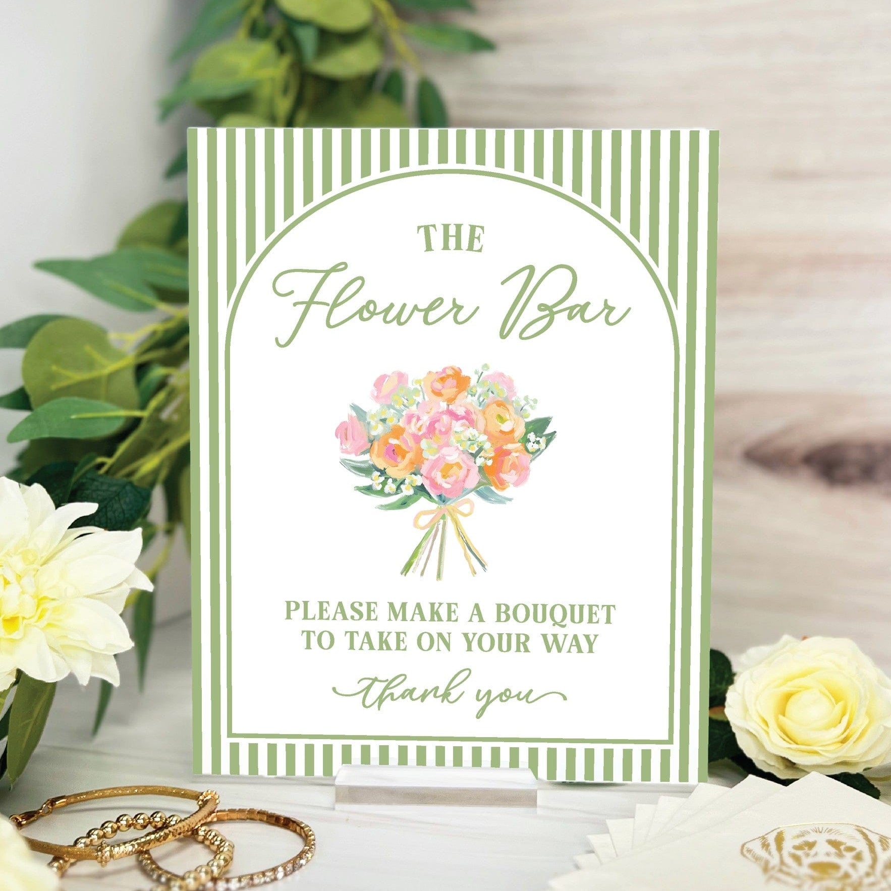 A rectangular table sign with a sage green and white striped border, featuring a delicate watercolor bouquet illustration, provides instructions for a flower bar at a wedding or event.