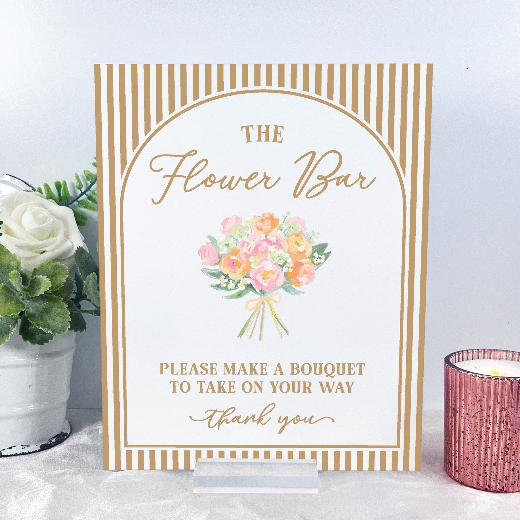 A white and gold striped table sign features an elegant arched frame with a watercolor bouquet illustration, standing on a clear acrylic base, perfect for a flower bar station at a wedding or bridal shower.