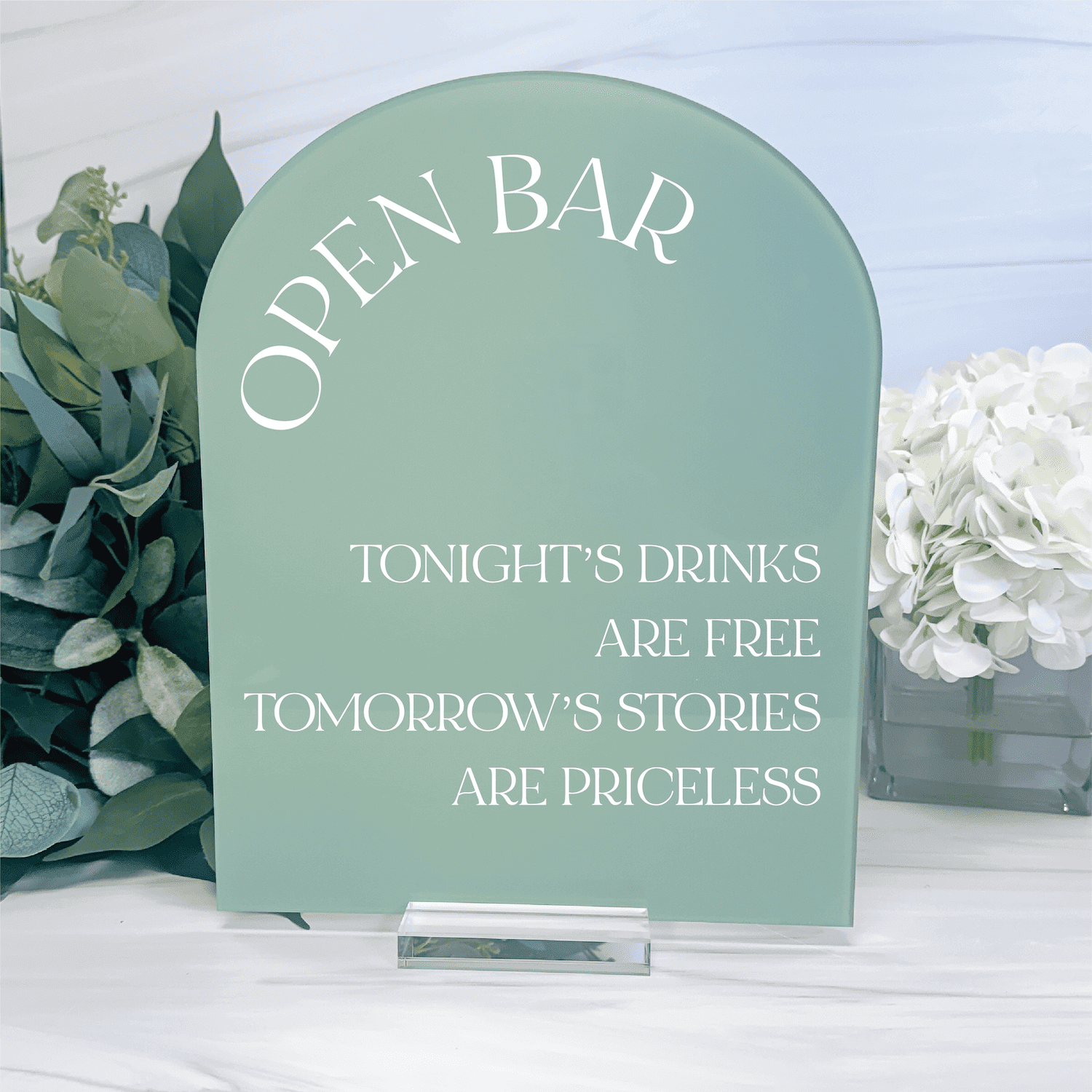 Sage green acrylic arch-shaped sign with white text reading "Open Bar," "Tonight's Drinks Are Free," and "Tomorrow's Stories Are Priceless"
