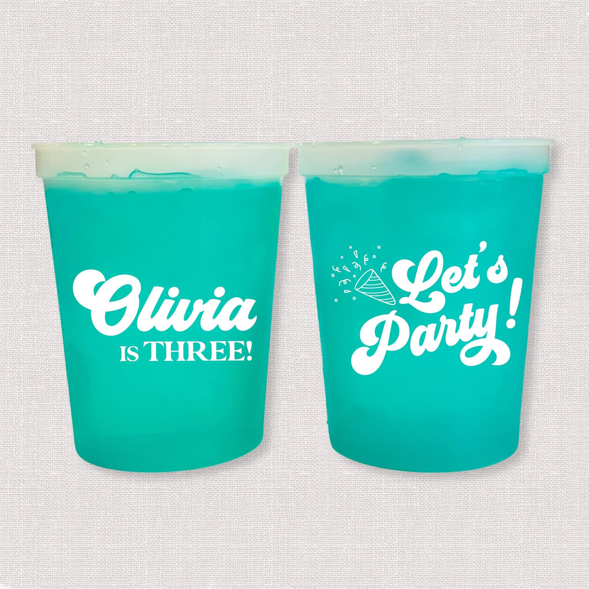 Teal color changing kids birthday stadium cups with Olivia is Three name and Let's Party design