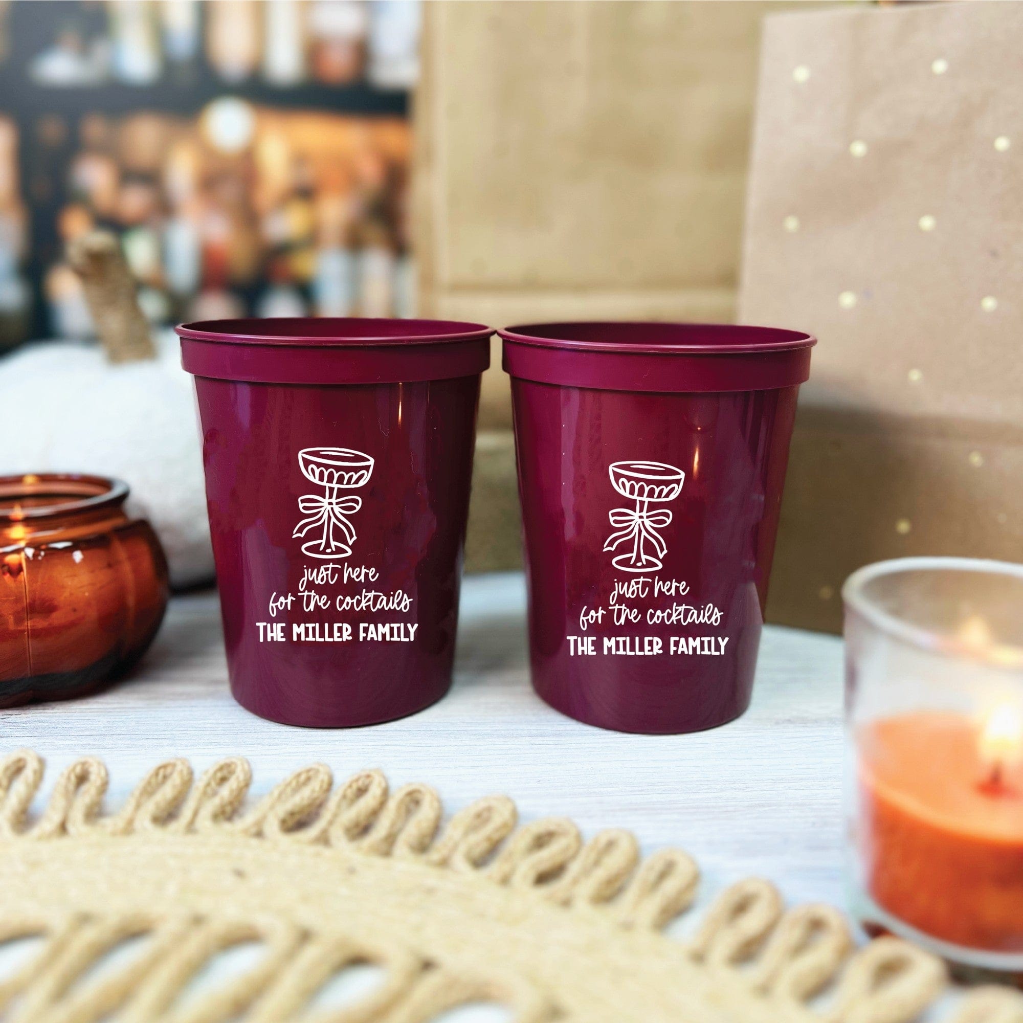 Two personalized burgundy plastic cups for event decor, each featuring a white stylized cocktail glass design with a ribbon and custom messaging.