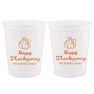 Two frosted white reusable plastic cups feature an orange pumpkin design, ideal for a Thanksgiving event or fall celebration.