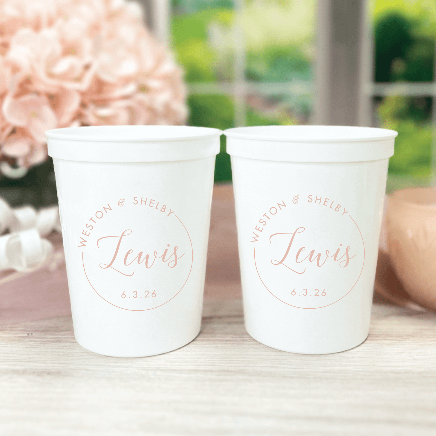 Two white stadium cups with rose gold circular monogram design reading "Shelby & Shelby Lewis" and wedding date "6.3.26"
