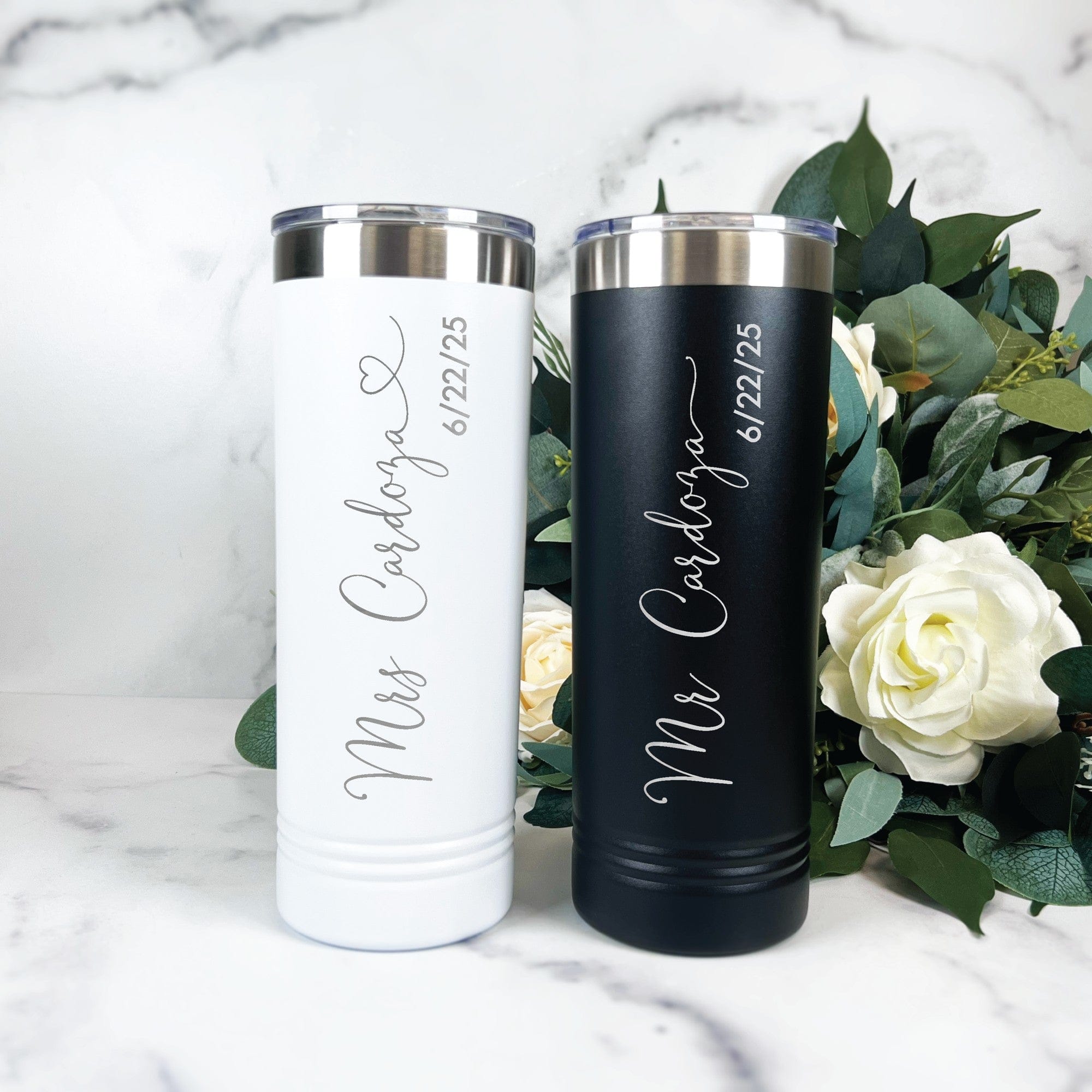 A pair of white and black personalized stainless steel tumblers with silver lids, ideal for a wedding or bridal event.