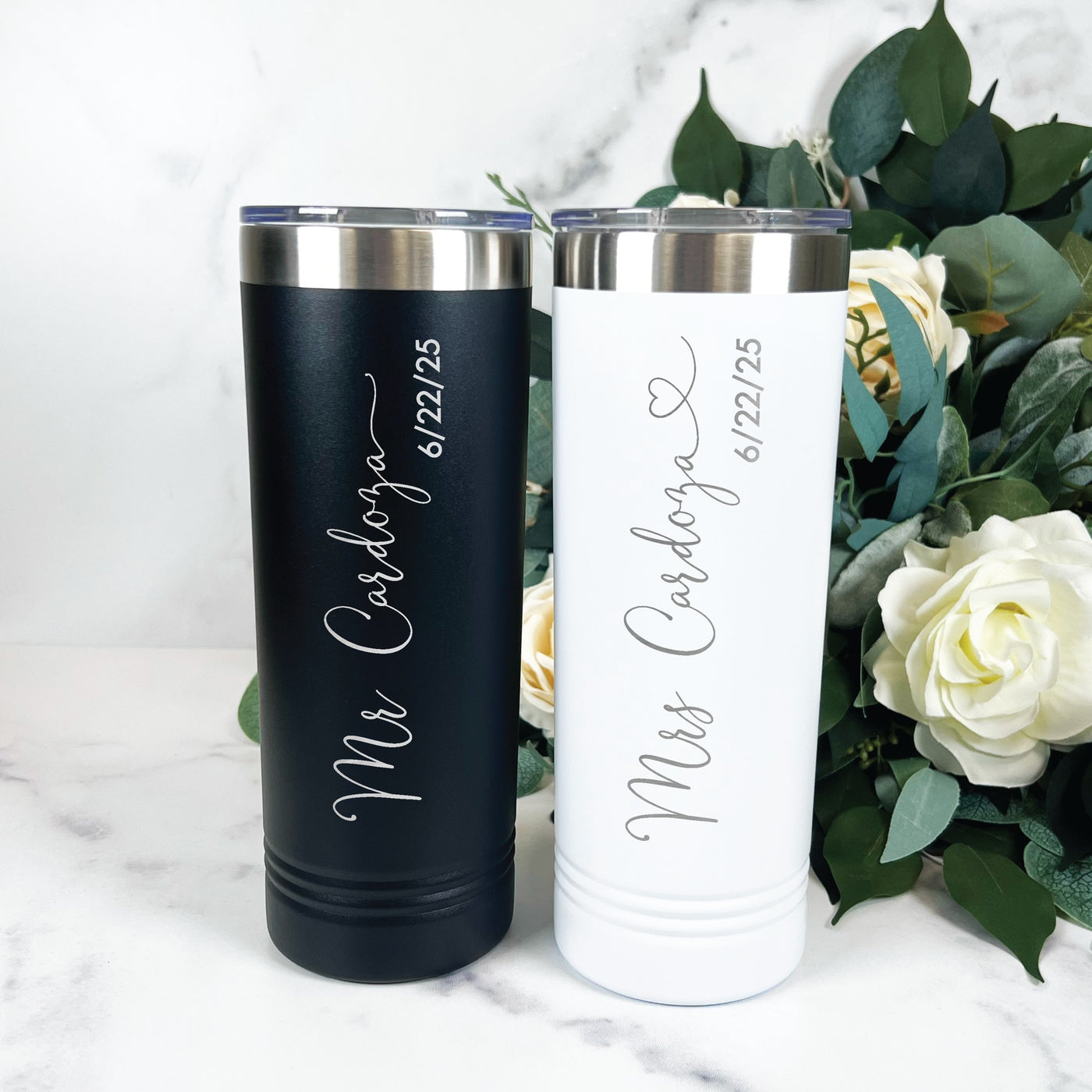 A pair of personalized matte black and white insulated tumblers with silver lids, perfect as a custom wedding gift or couple's keepsake.