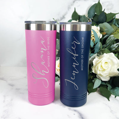 A pair of personalized stainless steel tumblers, one pink and one navy, each with silver etched script and a clear lid, ideal for wedding party gifts.