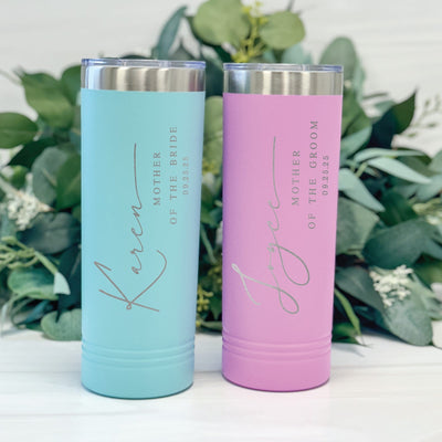 Two slim, insulated metal tumblers, one teal and one pink with metallic lids, designed as personalized gifts for a wedding party.
