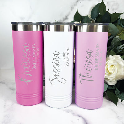 A set of three personalized insulated stainless steel tumblers in pink, white, and lavender, ideal as gifts for a wedding bridal party.