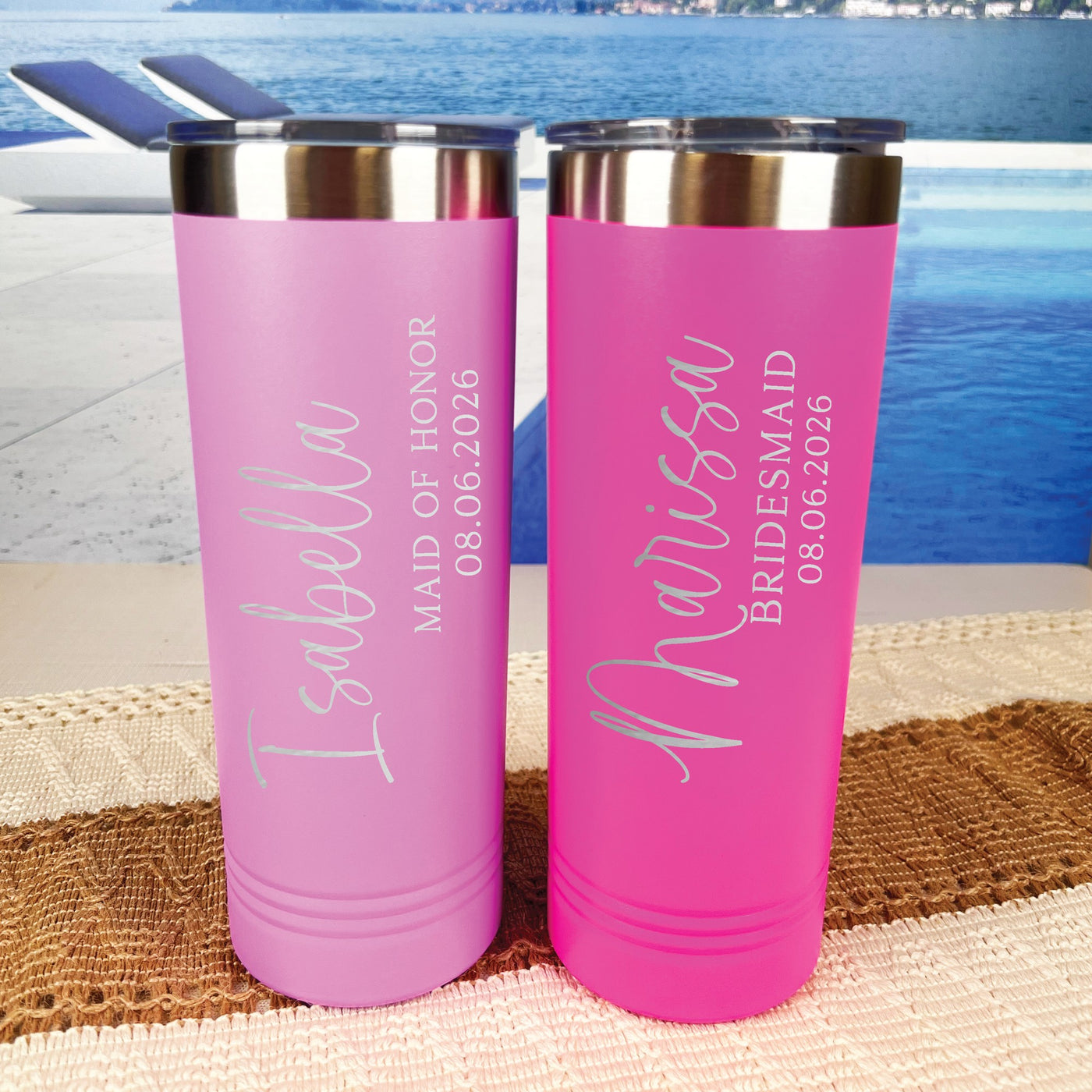 Two personalized pink insulated tumblers with stainless steel lids are displayed against a serene poolside background, perfect for a wedding party.