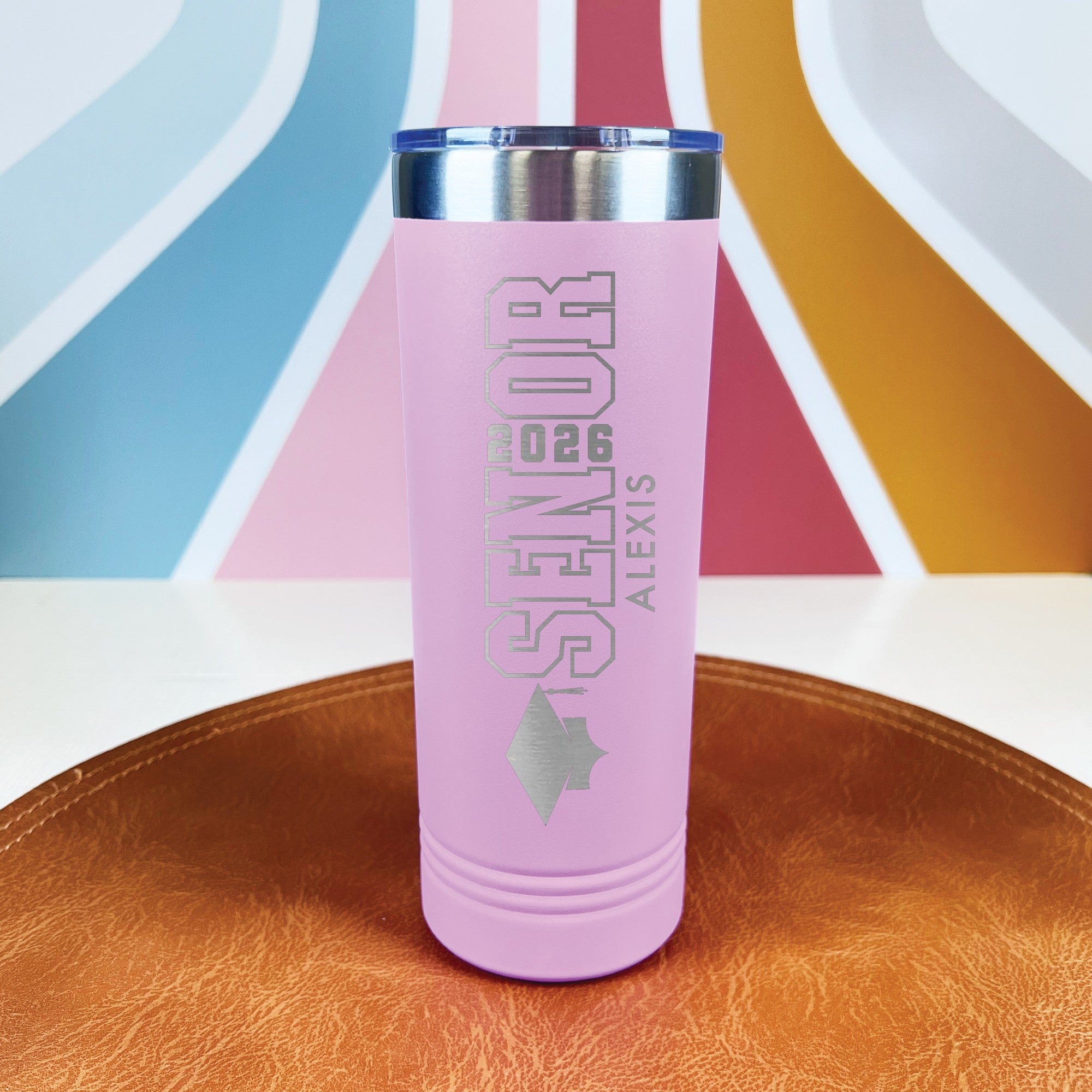 A light pink insulated metal tumbler with a silver lid, personalized with engraved text and a graduation cap design, perfect for a graduation celebration.