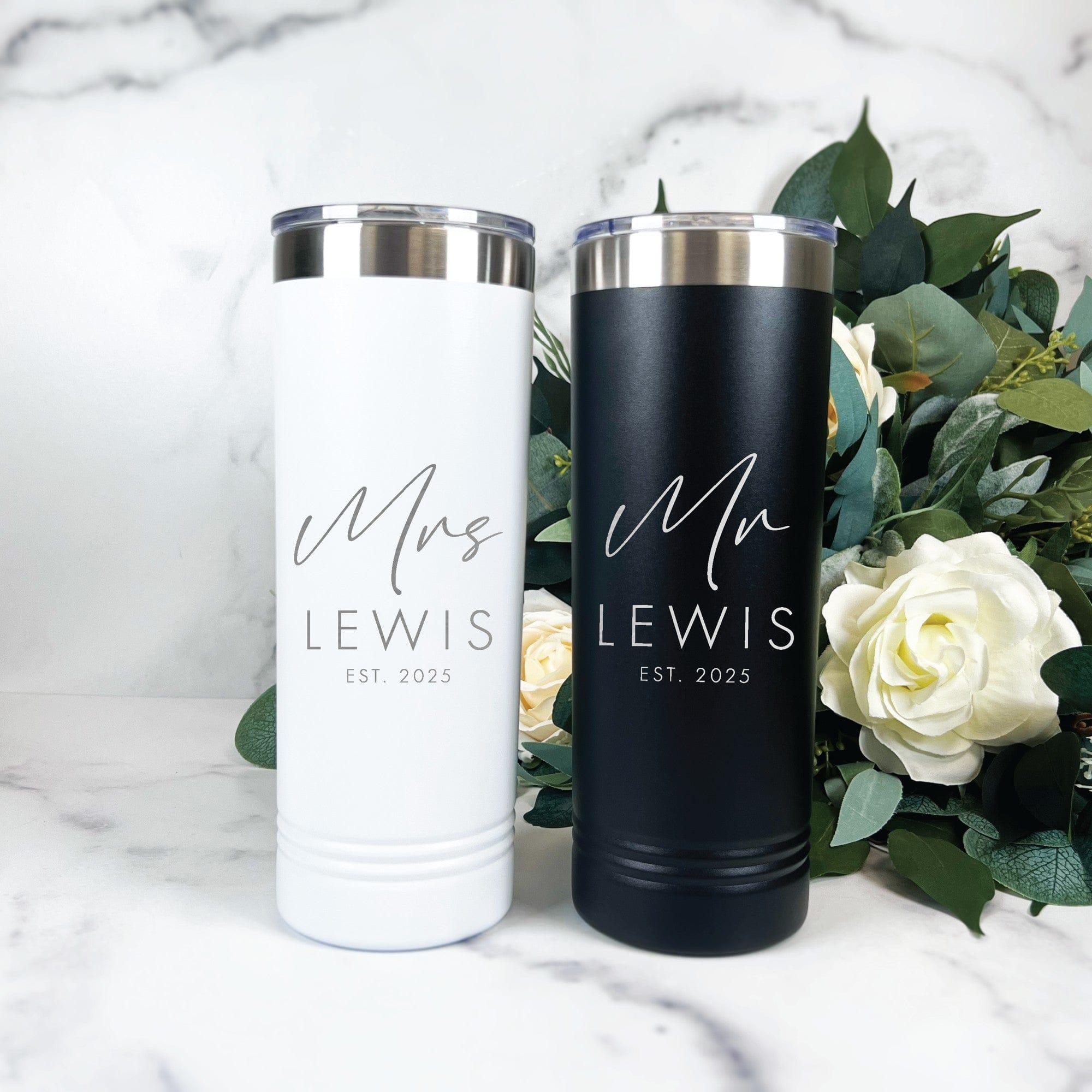 A set of personalized white and black insulated stainless steel tumblers with silver lids, designed as matching wedding or bridal shower drinkware.