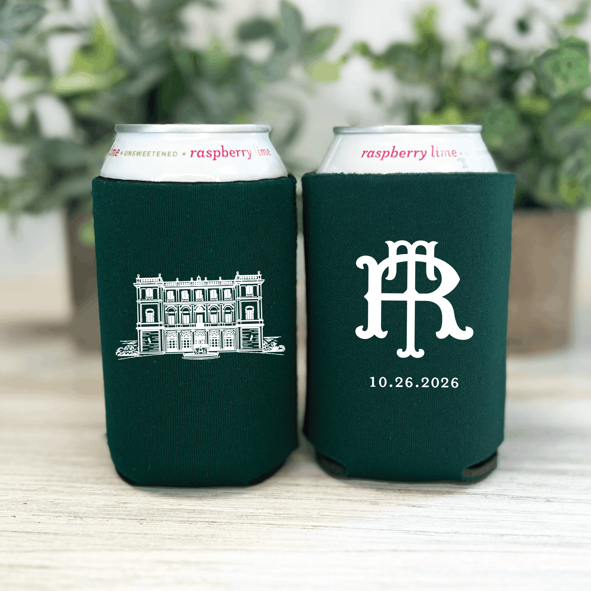 Dark green can coolers with white illustrated building and interlocking monogram design, dated 10.26.2026